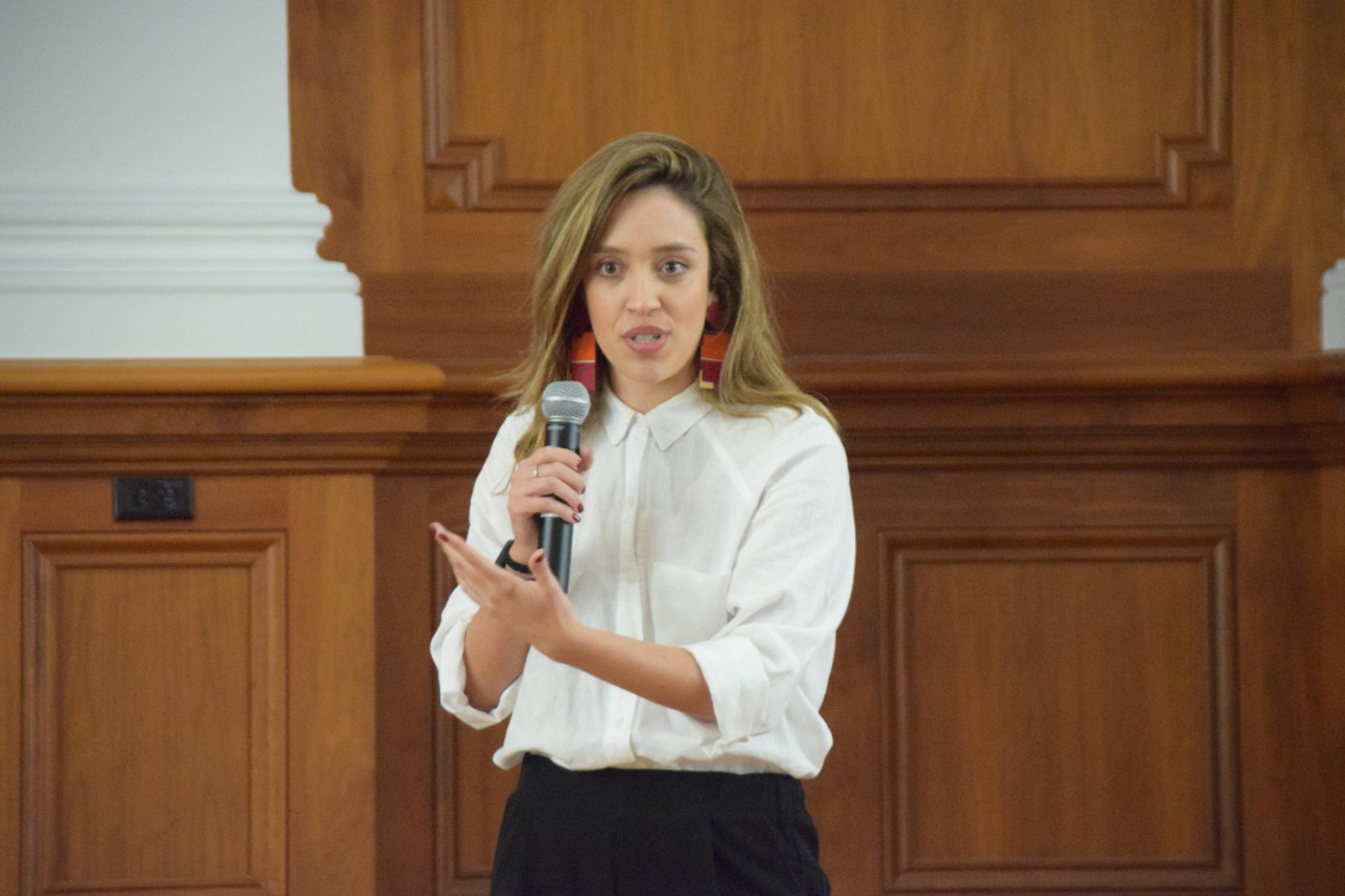 A graduate student delivers her three minute thesis speech on a stage.