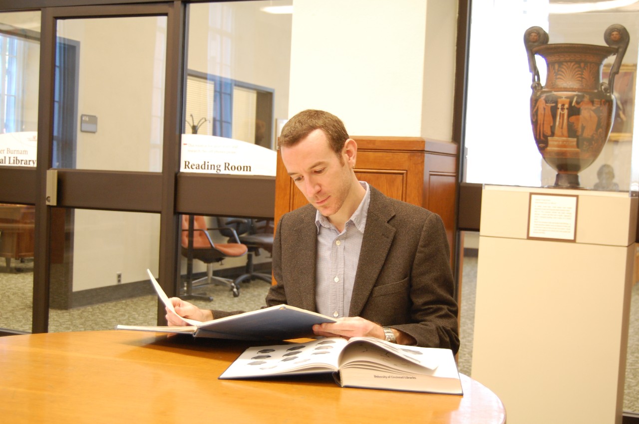 A student flips through a book in the Classics library.